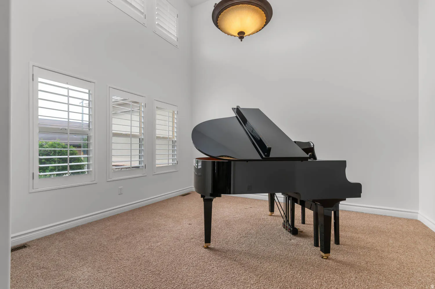 Room featuring vaulted ceiling, three windows with plantation shutters, additional high windows with plantation shutters, and carpet flooring