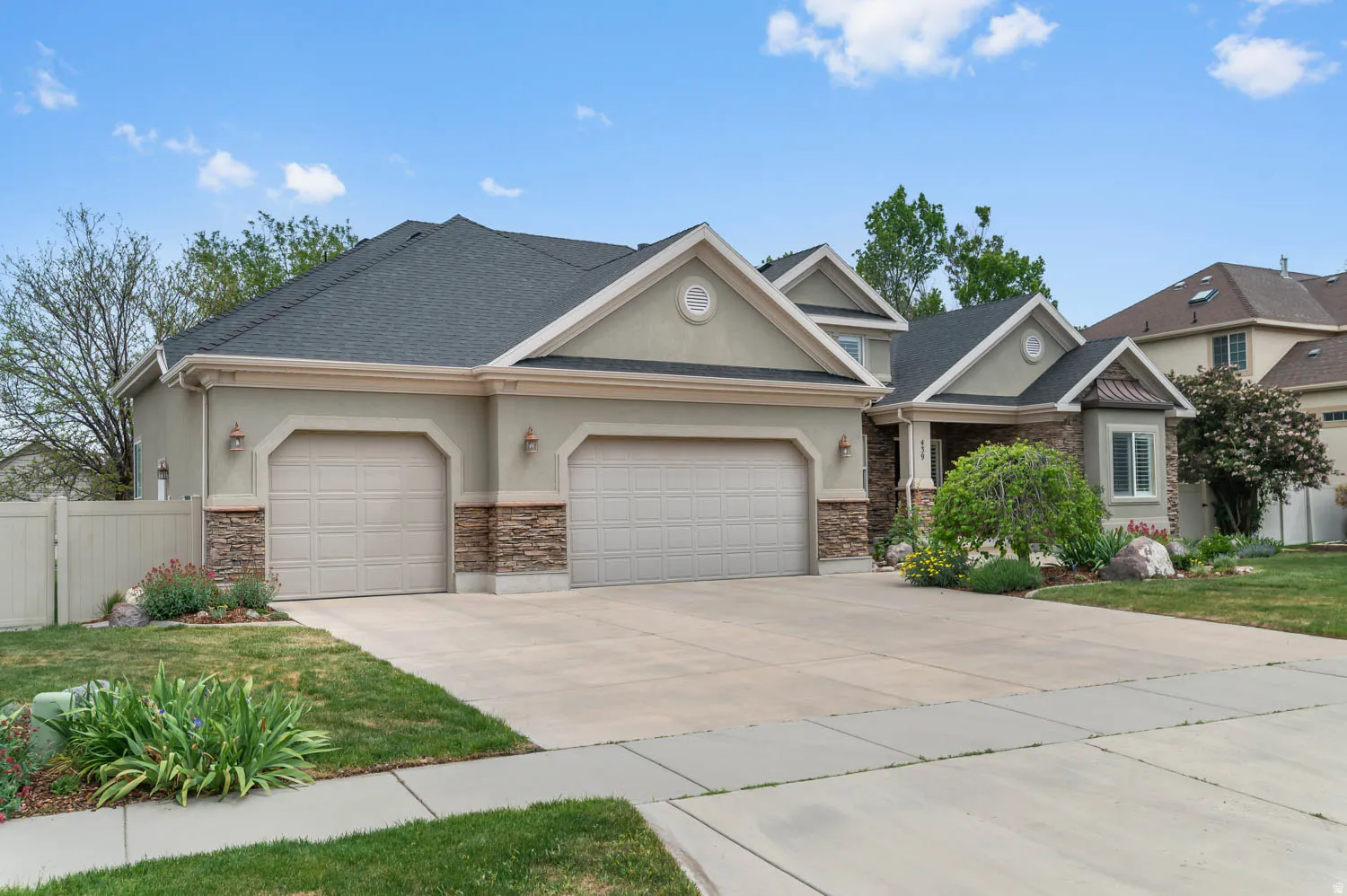 Stucco exterior with stone accents, a two-car garage, and a concrete driveway