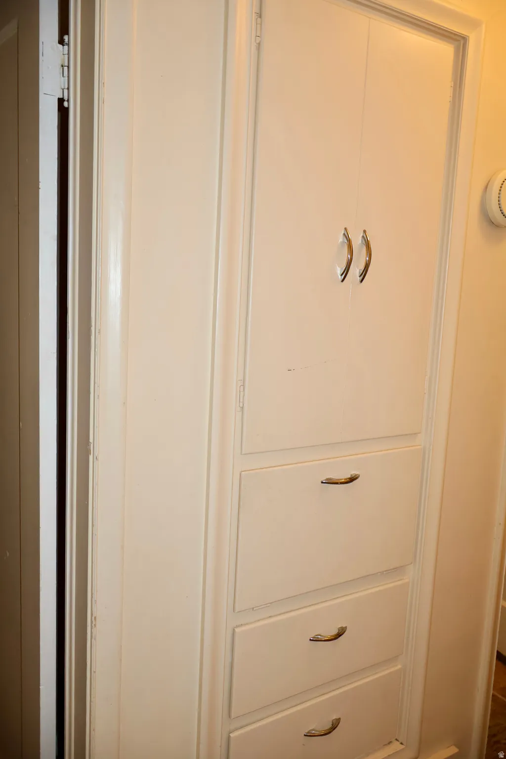 Built-in white cabinetry featuring two upper doors with curved handles and three lower drawers with coordinating hardware