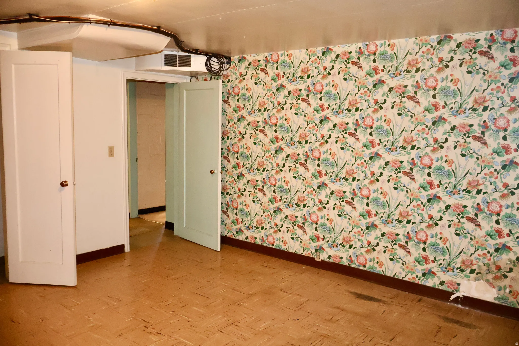 Room featuring wood-finish flooring, floral wallpaper, and two paneled doors