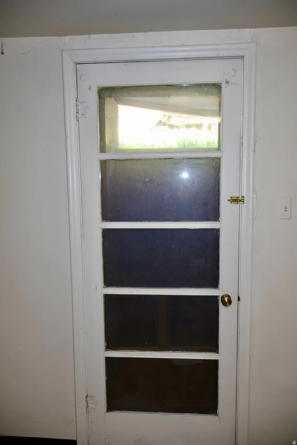 1st basement entrance. White paneled door with glass inserts and a brass doorknob