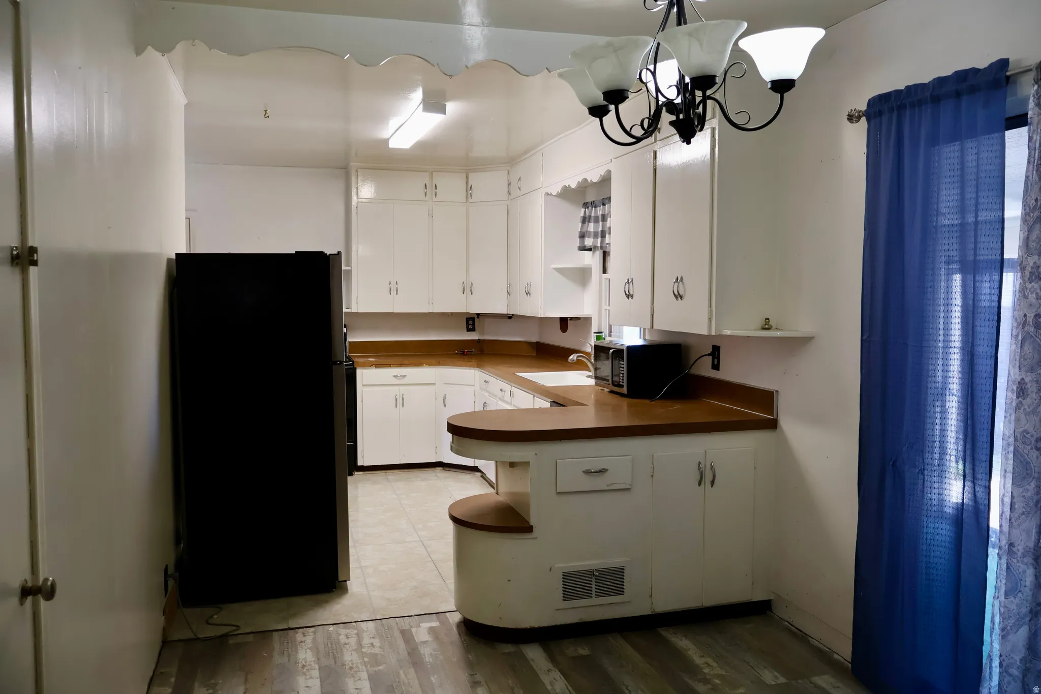 Kitchen featuring white cabinetry, wood-finish countertops, and a black refrigerator