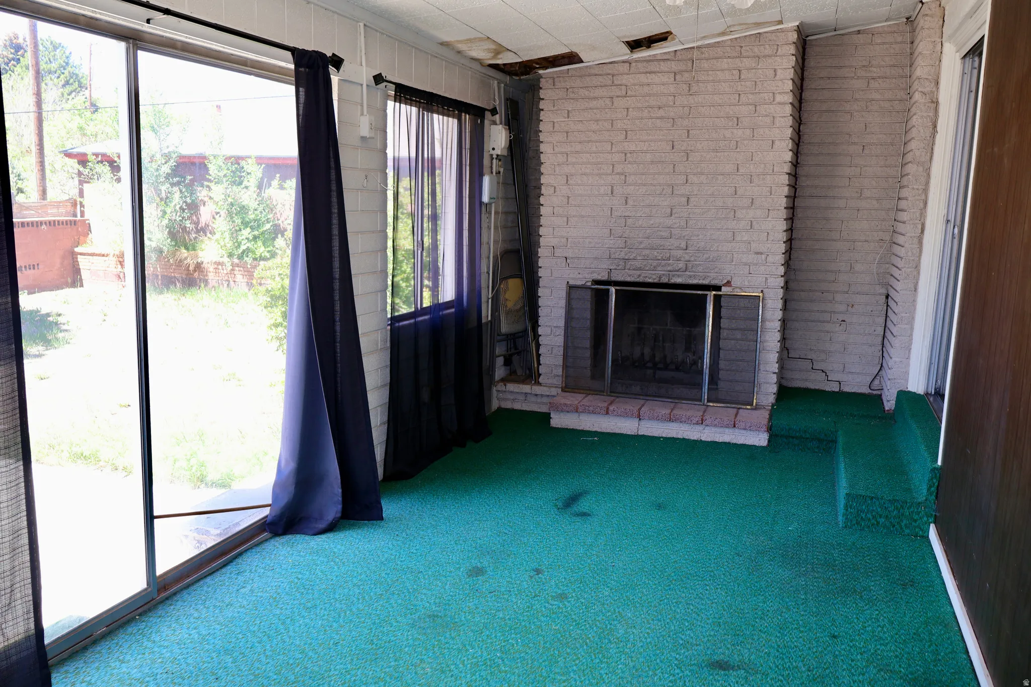 Sunroom featuring a brick fireplace with a raised hearth, sliding glass door, and additional window