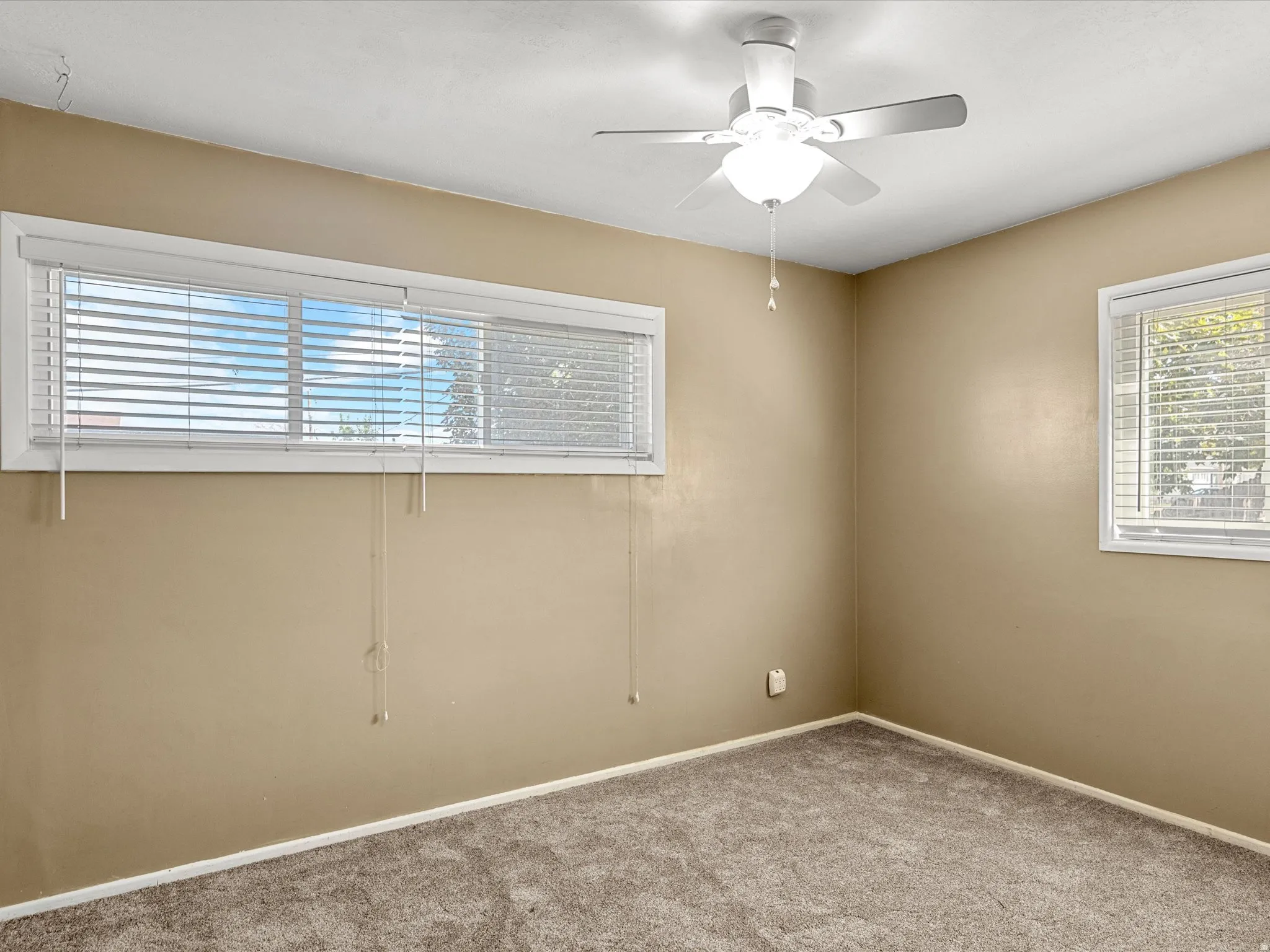 Room featuring neutral-toned walls, carpeted flooring, and a ceiling fan with integrated lighting