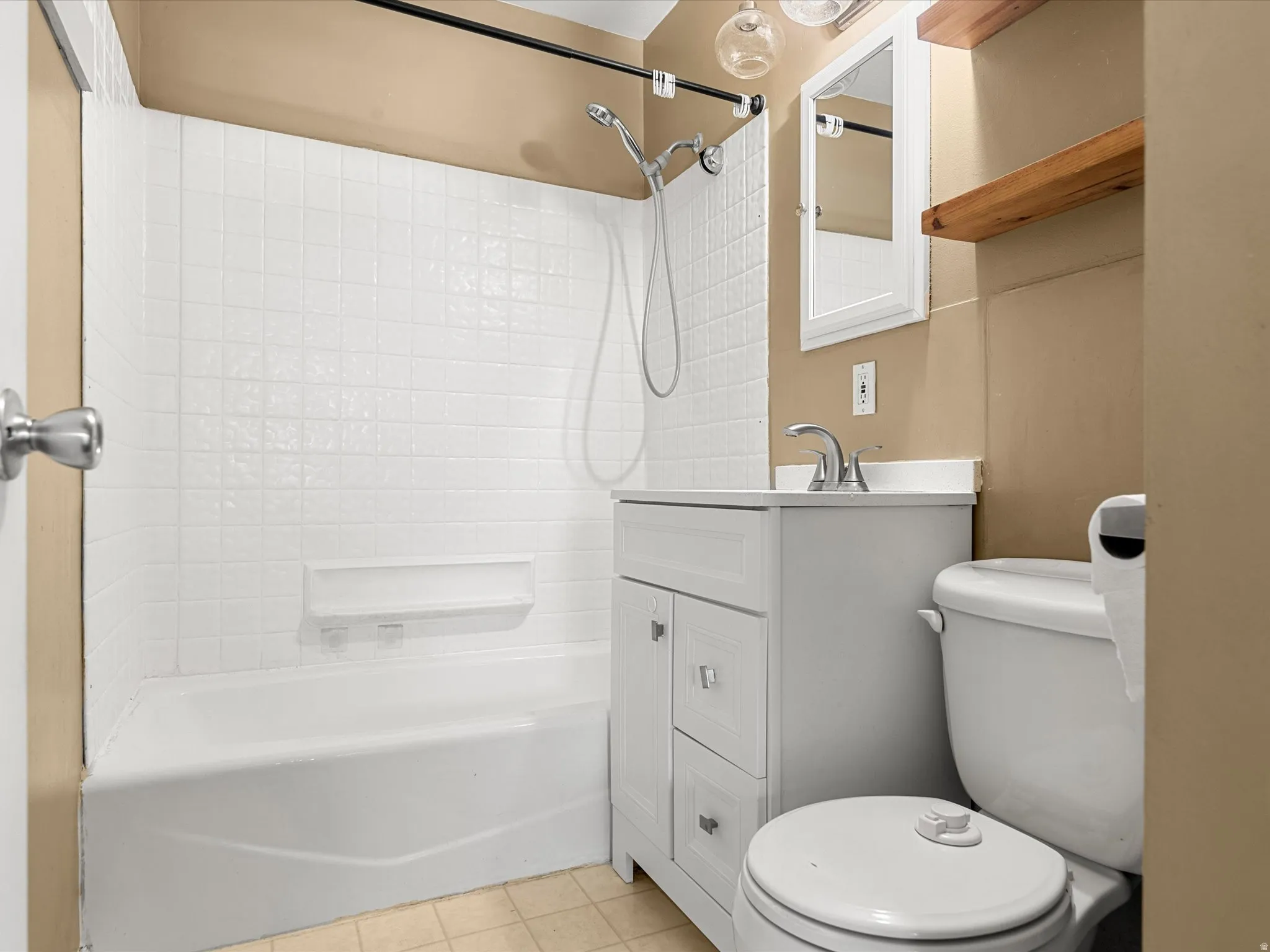 Bathroom featuring a white subway tile shower surround, a white vanity with silver hardware, and a white toilet