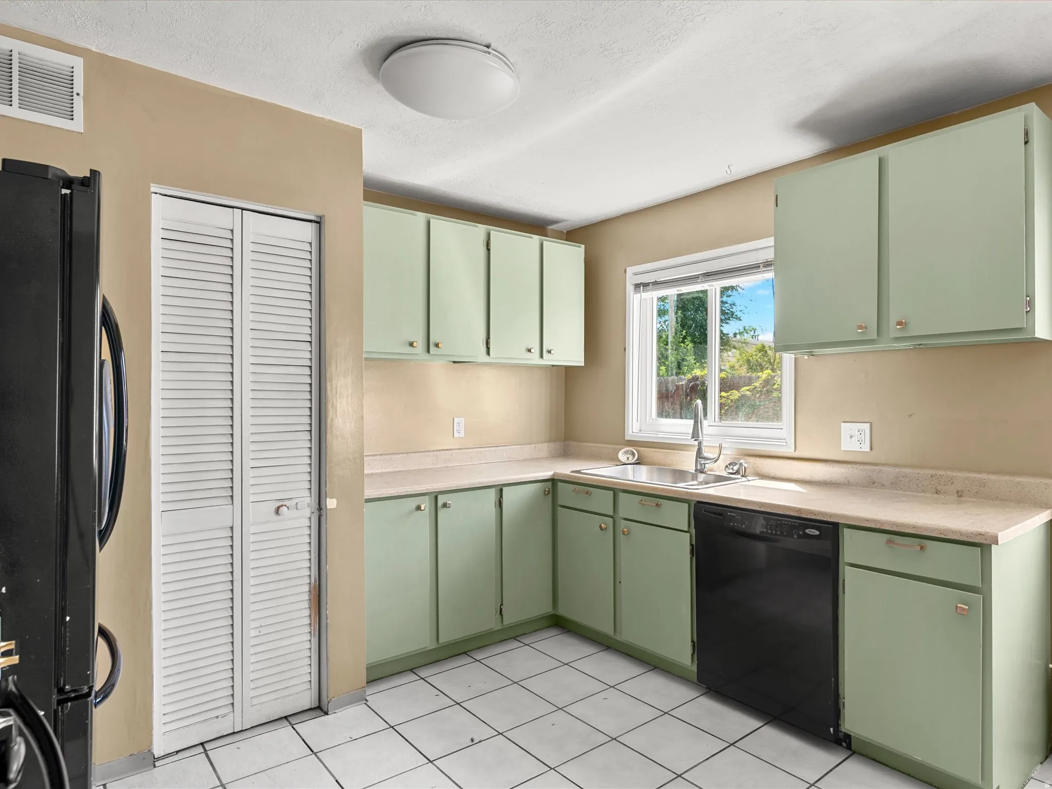 Kitchen featuring a double basin stainless steel sink, black dishwasher, and white tiled flooring
