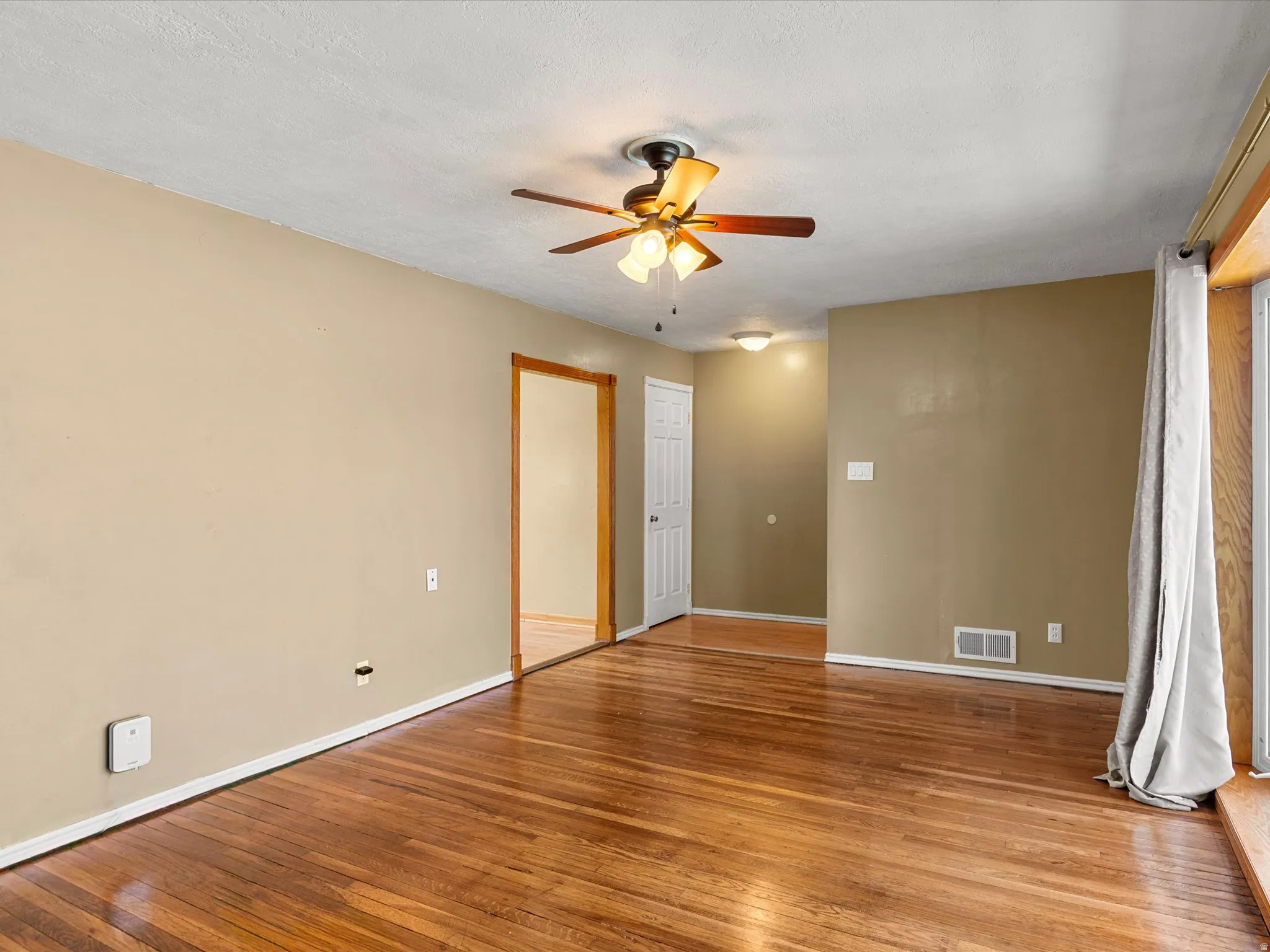 Spacious room featuring wood-finish flooring, light tan walls, and white trim