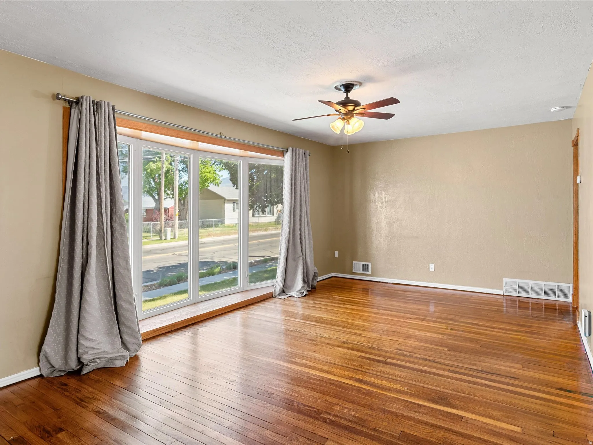 Hardwood flooring throughout featuring a multi-pane bay window