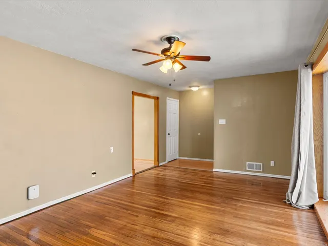 Spacious room featuring wood-finish flooring, light tan walls, and white trim