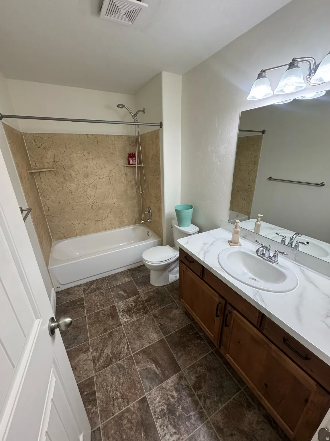 Bathroom featuring a single vanity with an integrated sink, a white countertop, and wood-finish cabinetry