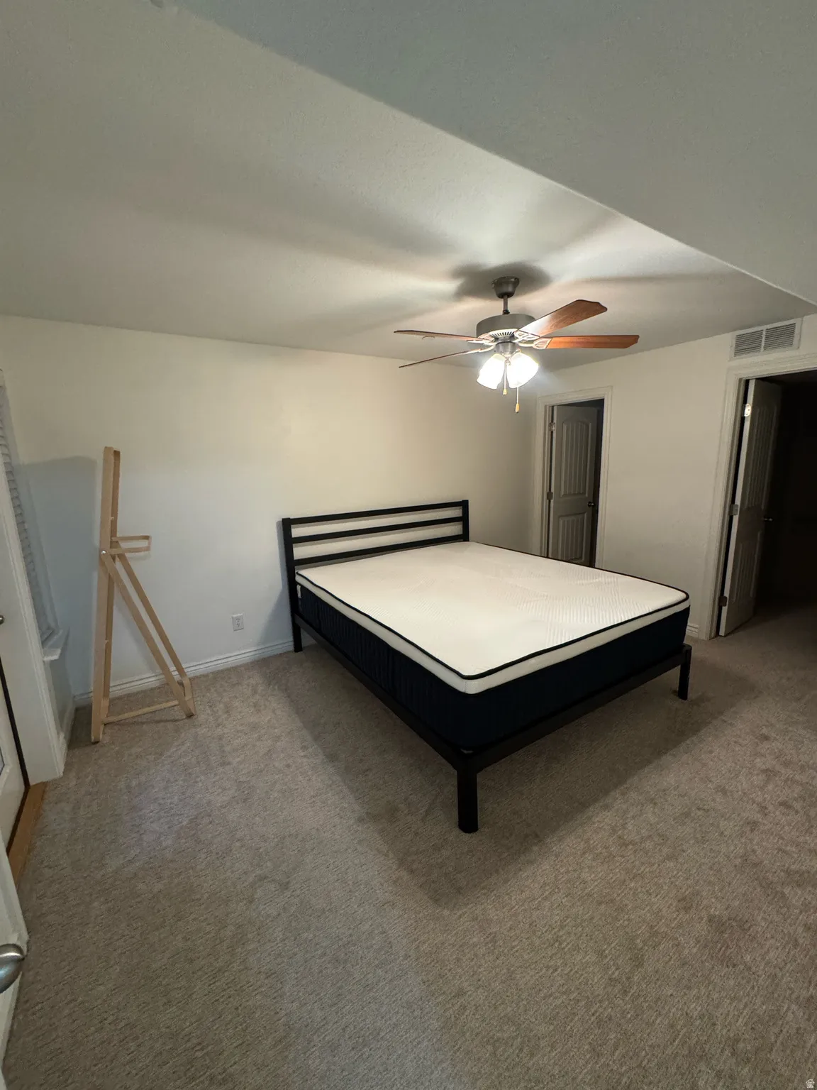 Carpeted room with a ceiling fan featuring a light kit and wood-finish blades