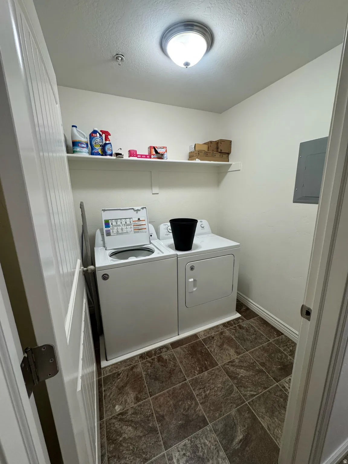 Dedicated utility space featuring a washer and dryer, tile flooring, and overhead shelving
