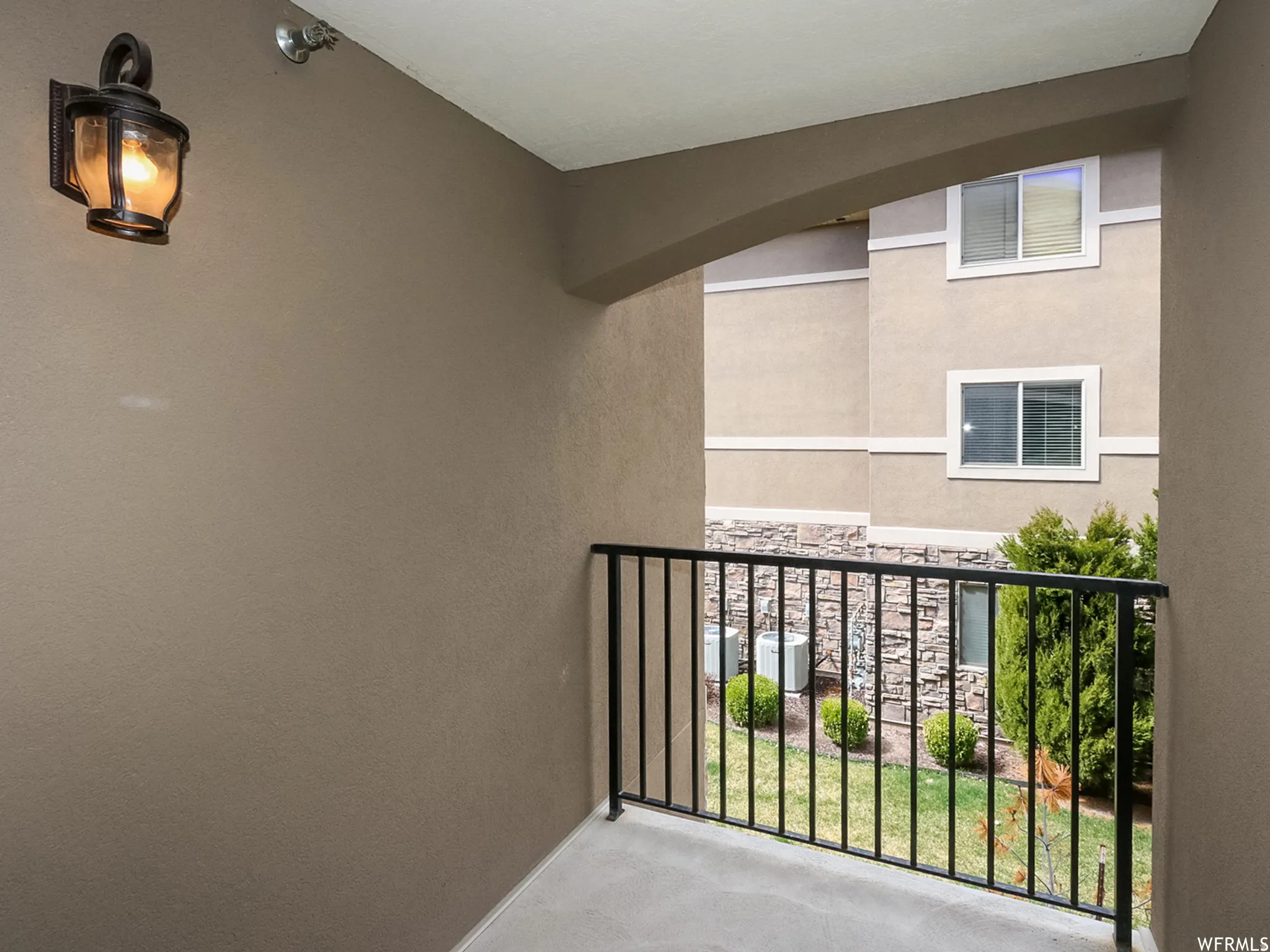 Private outdoor balcony featuring a wrought iron railing and a wall-mounted lantern light fixture