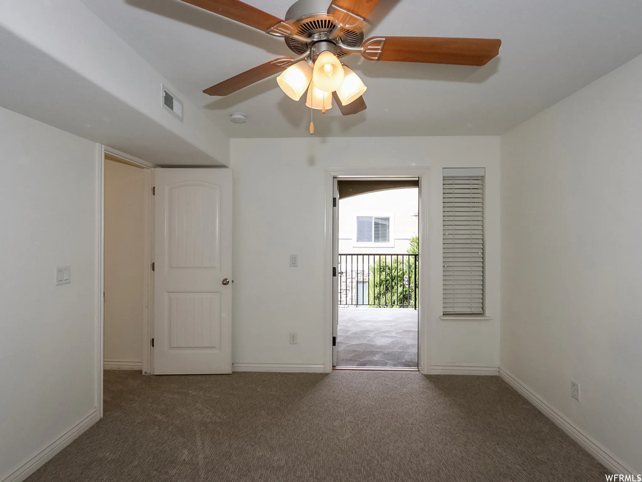 Spacious room featuring neutral carpeting, a ceiling fan with integrated lighting, and white walls