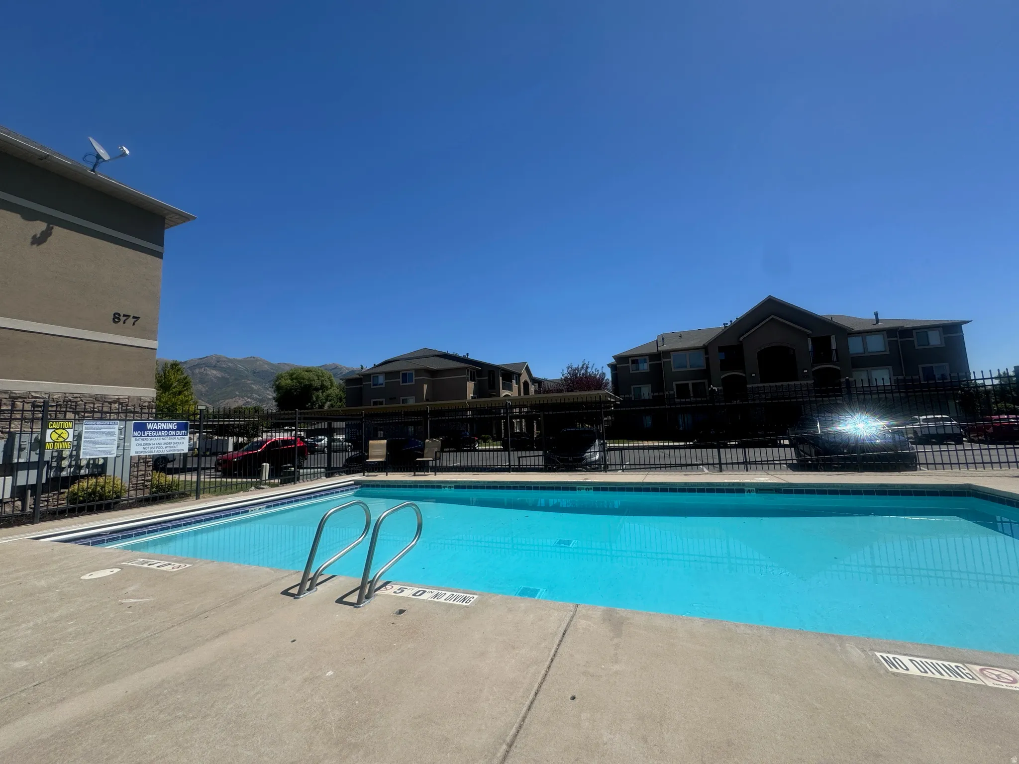 Inviting swimming pool with an integrated ladder, surrounded by a concrete deck and secure perimeter fencing