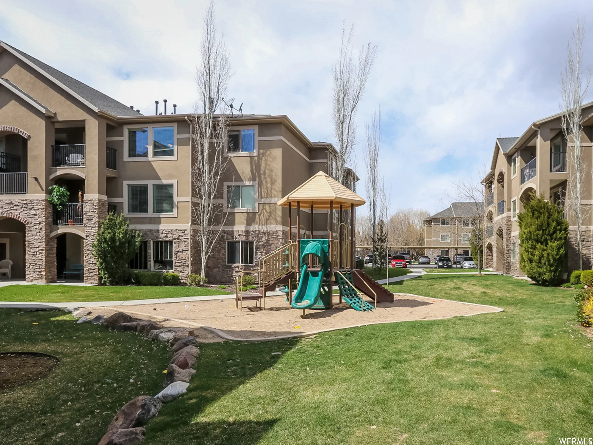 Community green space featuring a playground with slides and a sand area