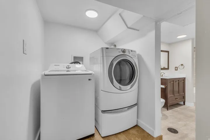 Dedicated laundry area featuring a white top-load washing machine and a white front-load dryer with a pedestal
