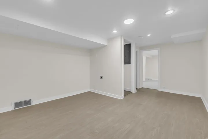 Spacious room featuring wood-finish flooring, recessed lighting, white walls, and white trim