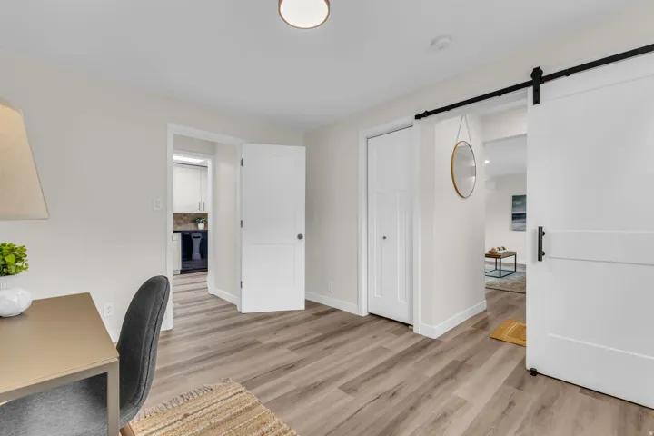 Wood-finish flooring throughout, featuring a modern barn door entry, white trim, and a bi-fold closet door