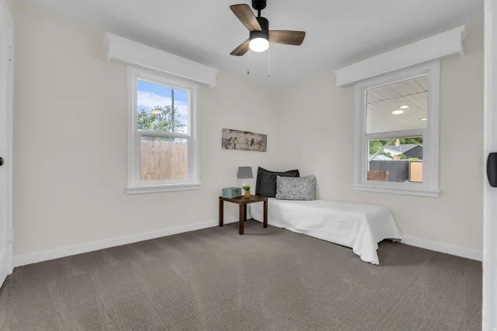 Carpeted room featuring two windows, crown molding, and a ceiling fan with light fixture