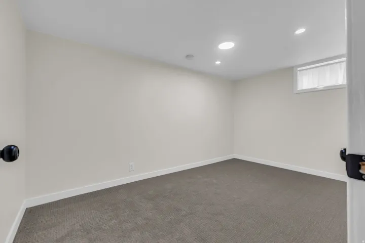Neutral-toned room featuring recessed lighting, a high window with white trim, and light gray wall-to-wall carpeting