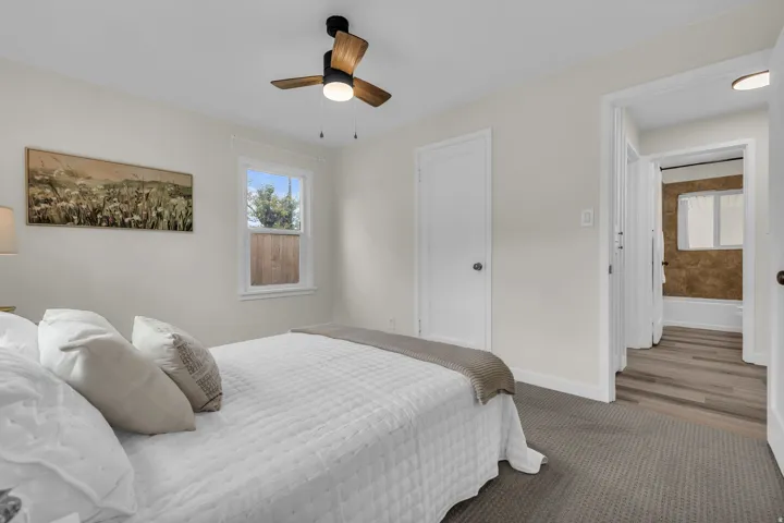 Bedroom featuring neutral wall tones, carpet flooring, a window offering natural light, and an overhead ceiling fan