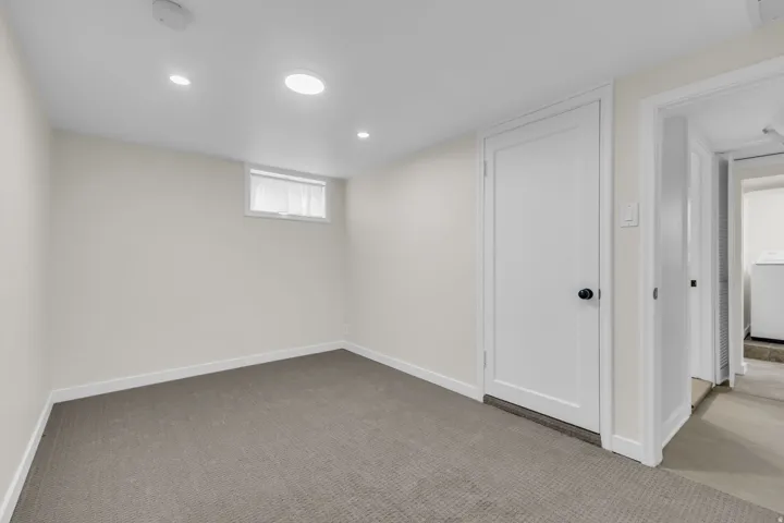 Carpeted lower-level room with recessed lighting and a white trim window