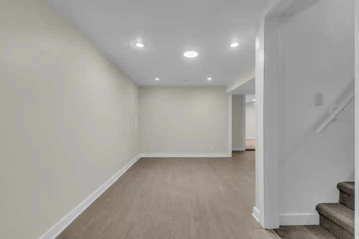 Spacious room featuring light wood-finish flooring, recessed lighting, and crisp white baseboards
