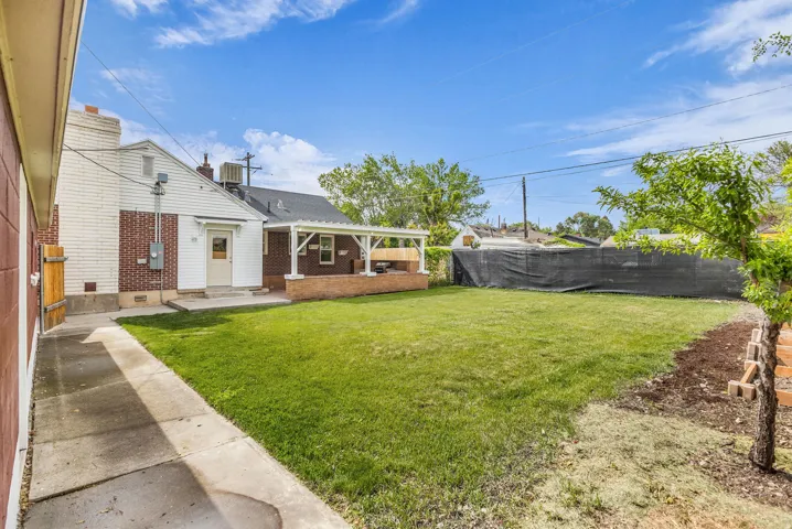Expansive backyard featuring a lush lawn, concrete patio, and a covered pergola