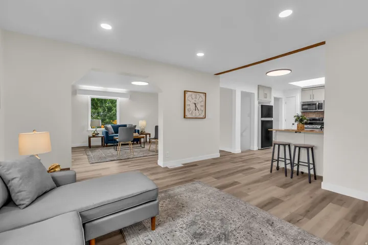 Expansive living area featuring wood-finish flooring, recessed lighting, and an arched doorway opening to an additional space