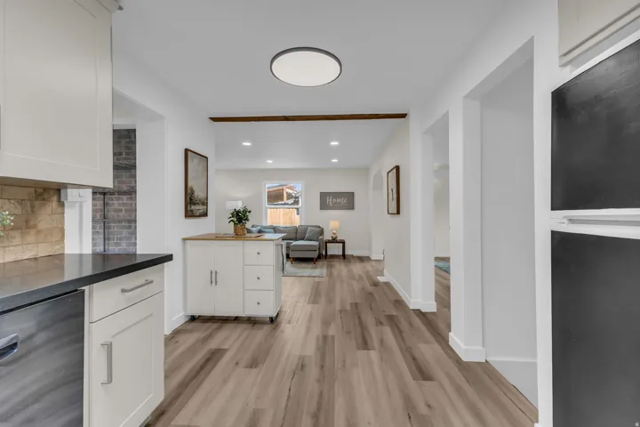 Modern kitchen area featuring white cabinetry, dark countertops, a stone-finish backsplash, and stainless steel appliances