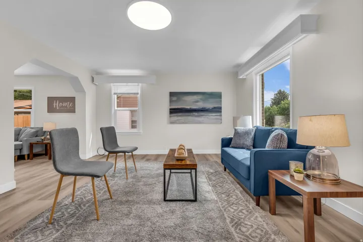 Bright living space featuring light wood-finish flooring, a contemporary flush-mount ceiling light fixture, and white wall finishes