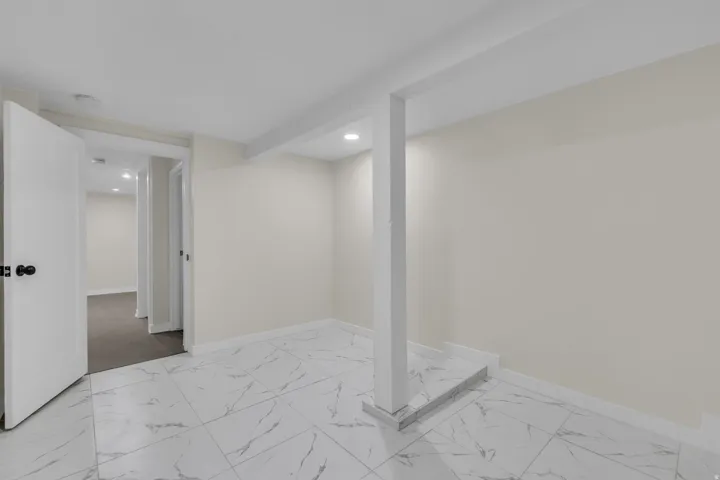 Spacious room featuring white walls, recessed lighting, and white tile flooring with grey veining