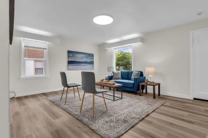 Bright living area featuring wood-finish flooring, white walls, and two windows