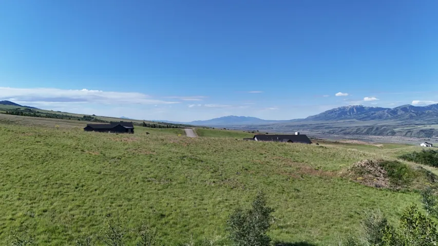 Expansive green terrain featuring distant mountain ranges and a clear sky