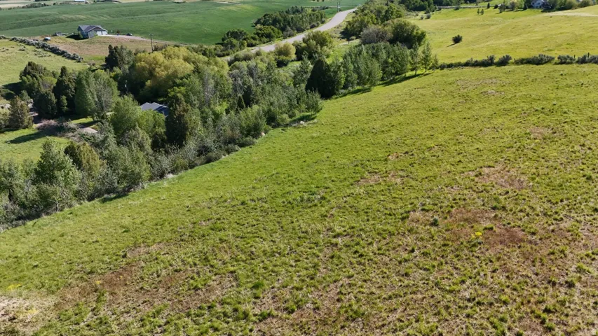 Expansive grassy terrain with rolling hills and distant agricultural fields