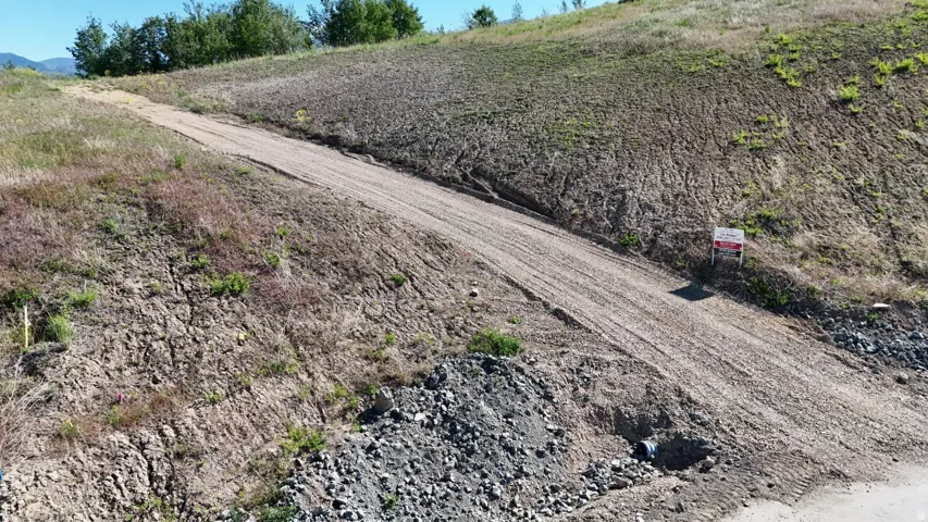 Sloping terrain featuring an unpaved access path and natural landscaping
