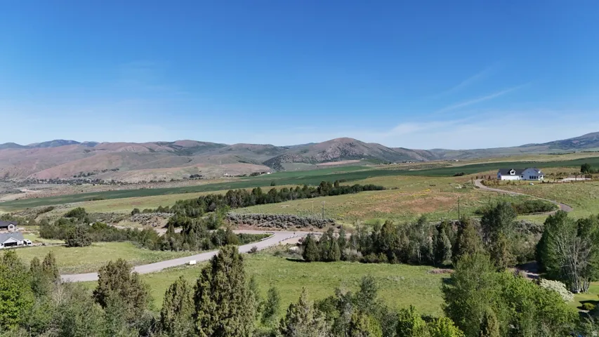 Expansive landscape featuring rolling hills, distant mountains, and scattered residential properties