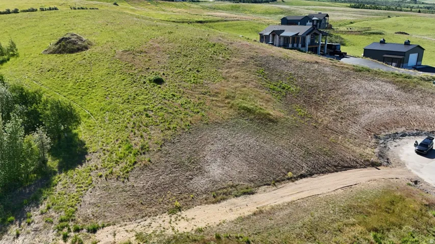 Expansive open land with varied topography, including areas of green foliage and exposed earth