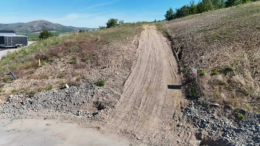 Expansive undeveloped lot featuring a natural terrain slope and a partial dirt access path