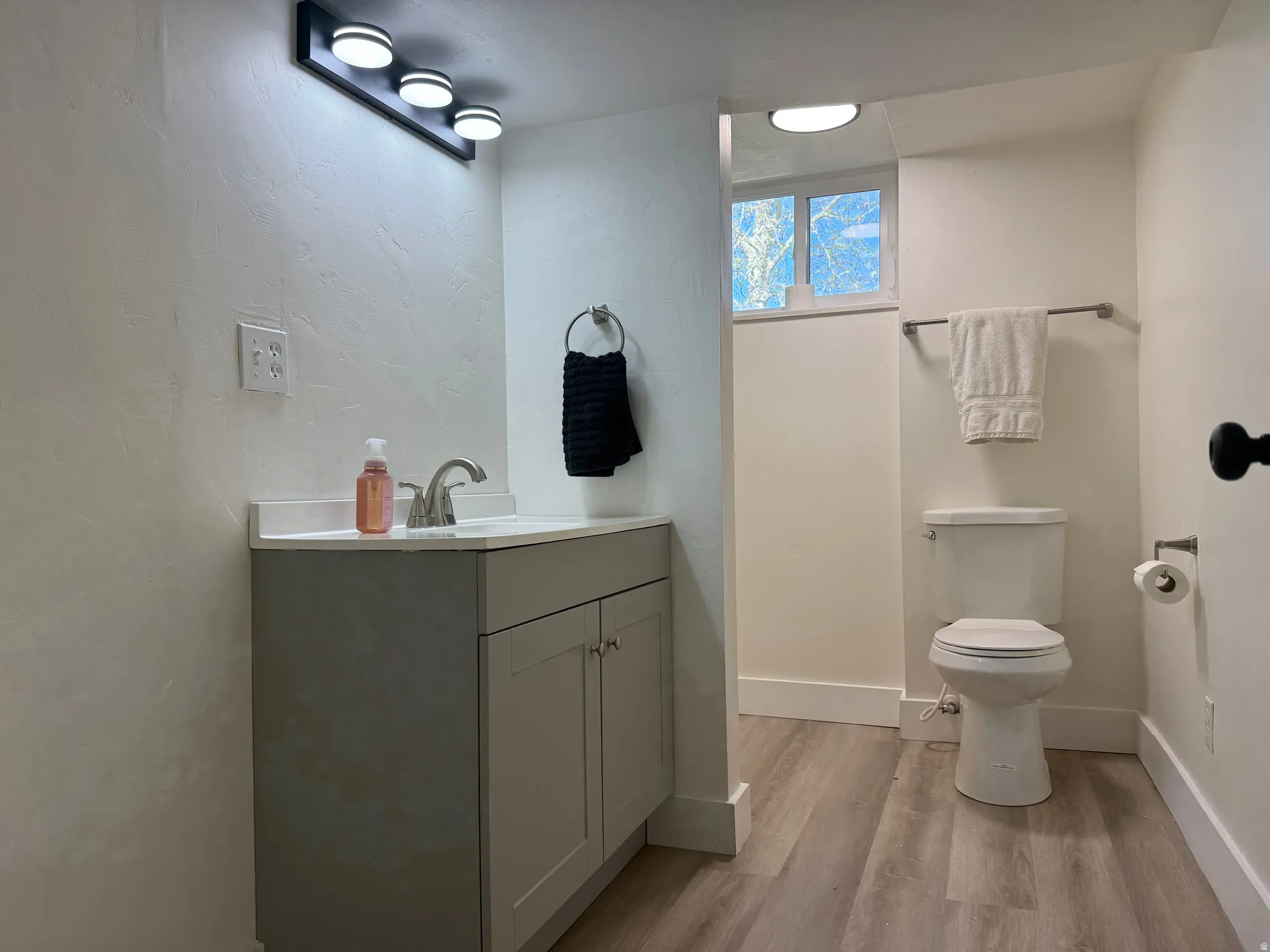 Bathroom featuring a light gray vanity with a white countertop, chrome faucet, and a three-light vanity fixture