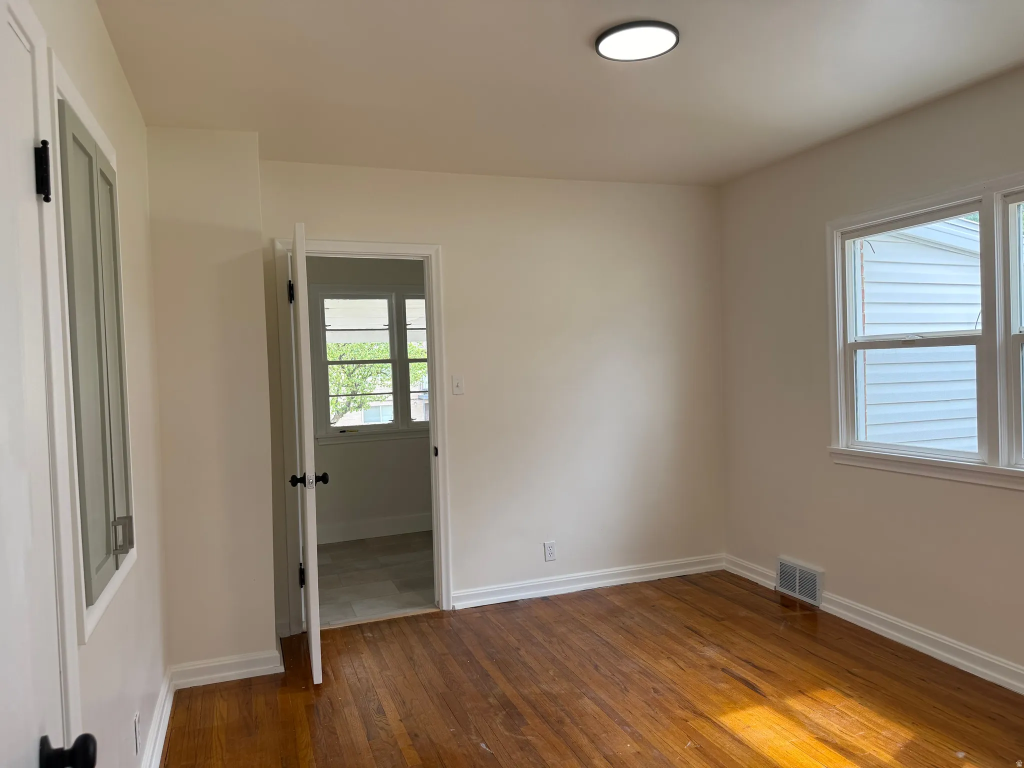 Room featuring wood-finish flooring, neutral wall tones, and white trim
