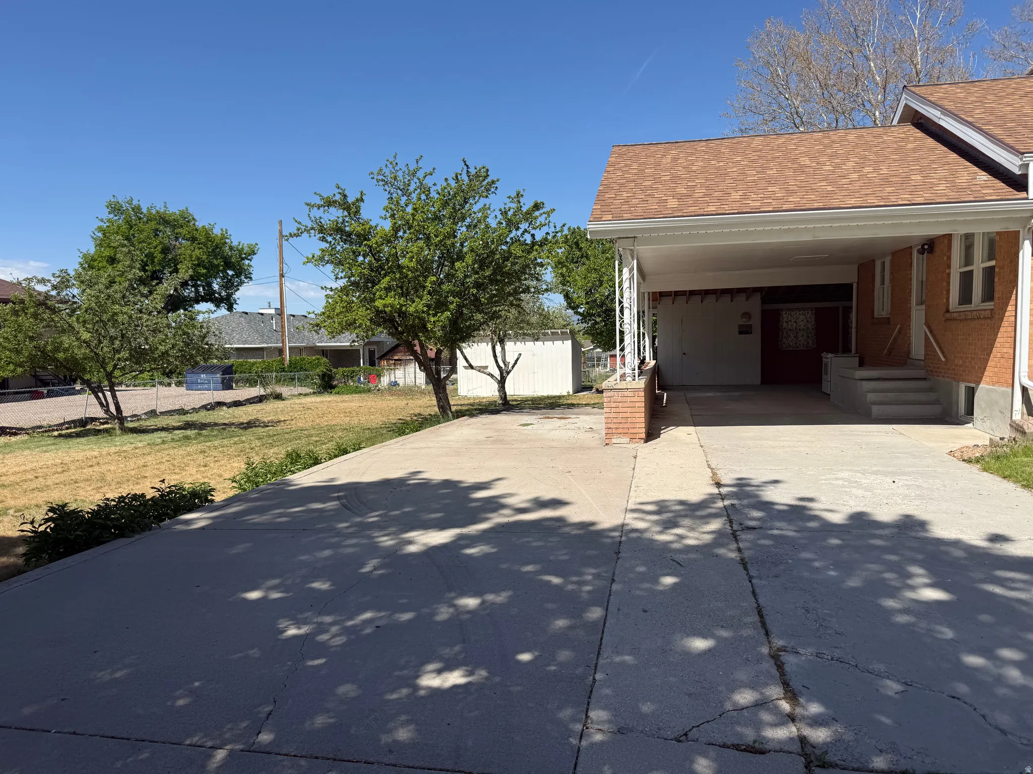 Brick exterior with a covered carport, concrete driveway, and concrete steps leading to the entry