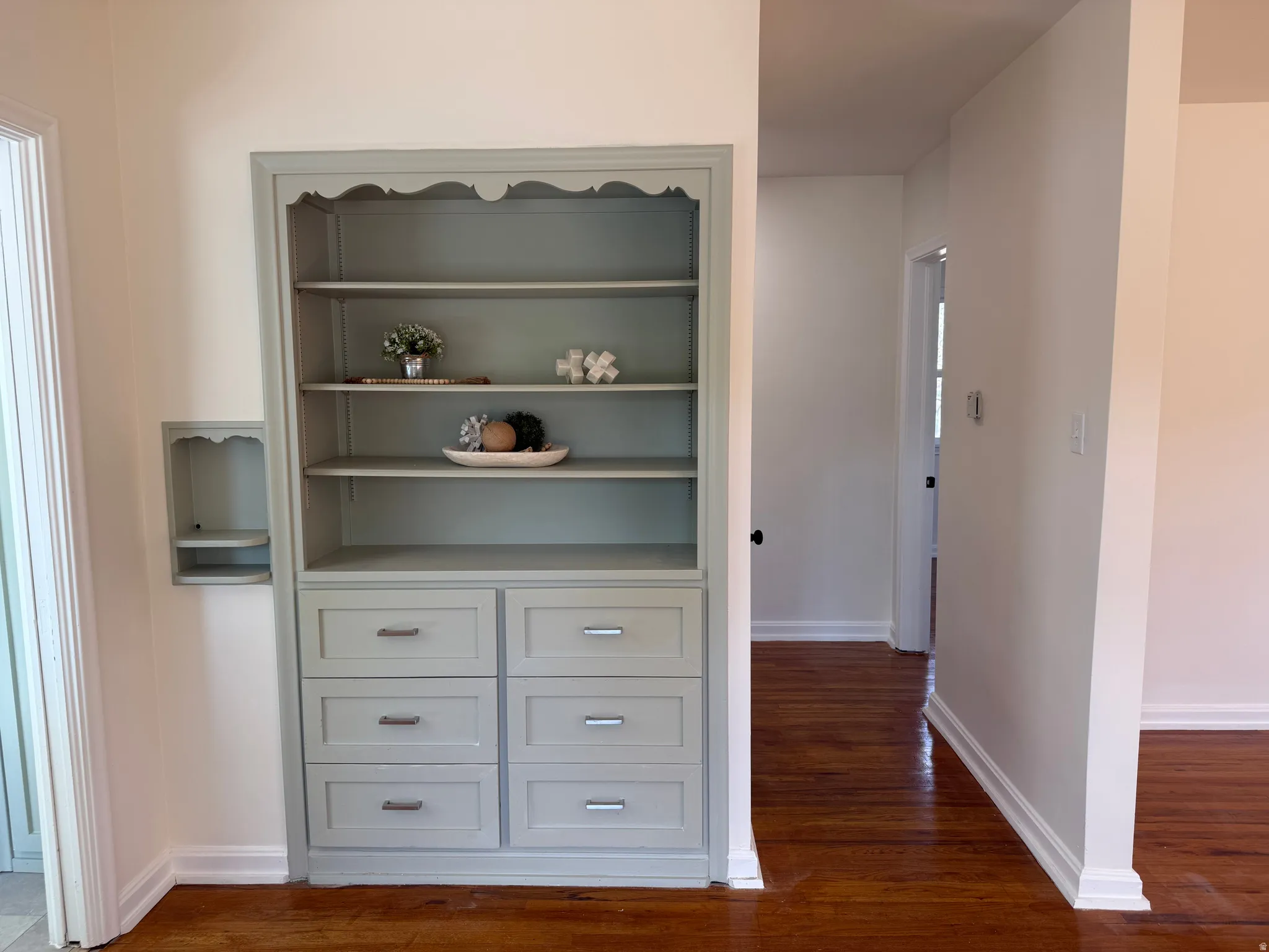 Built-in shelving unit with decorative trim, integrated drawers, and a complementary wall niche