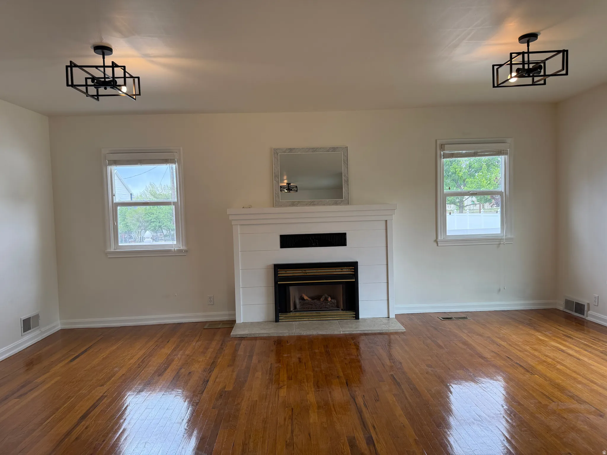 Living area featuring a fireplace with a white shiplap-style surround, a light-toned hearth, and rich wood-finish flooring