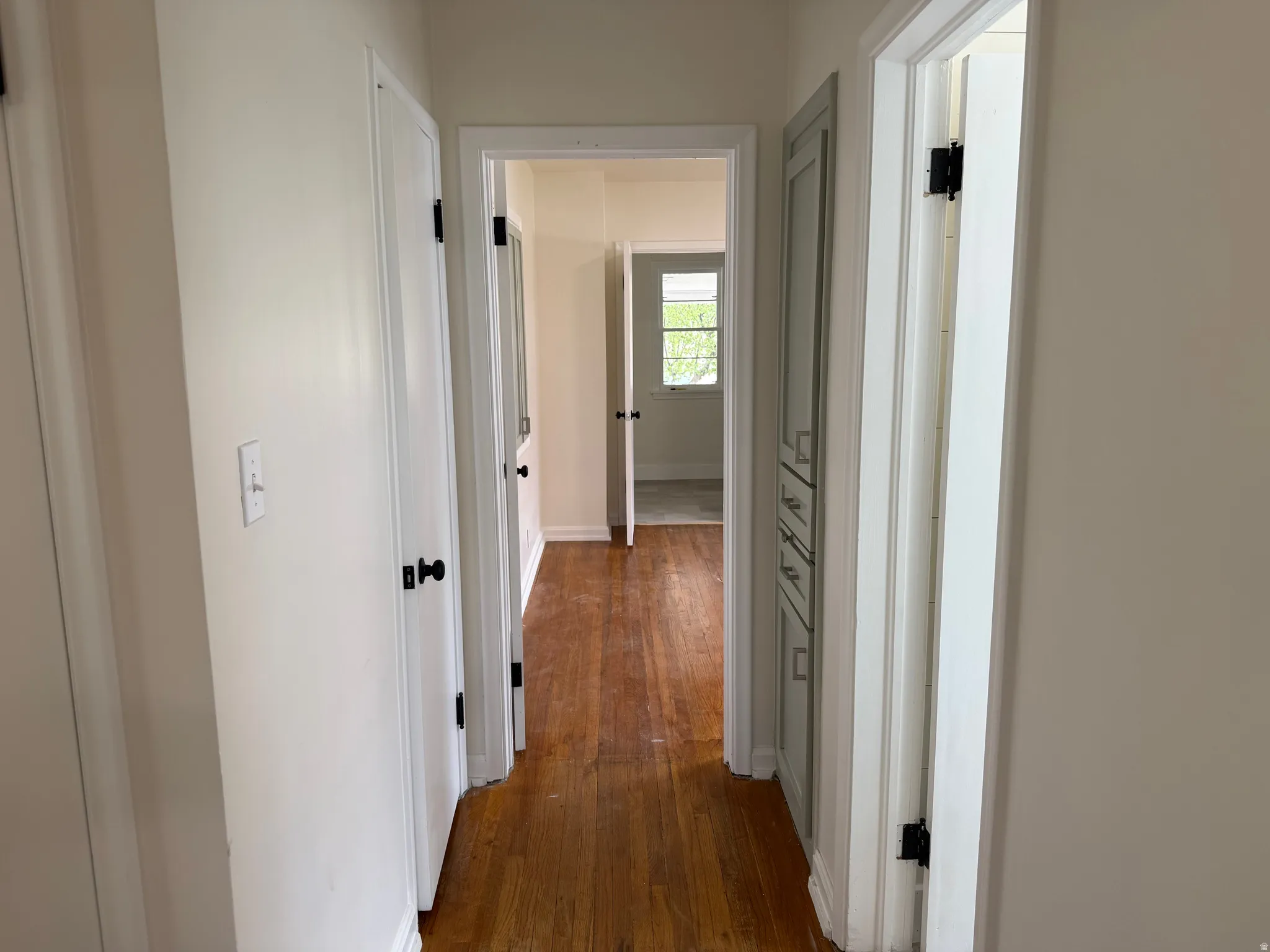 Hallway featuring wood-finish flooring, white walls, and white trim