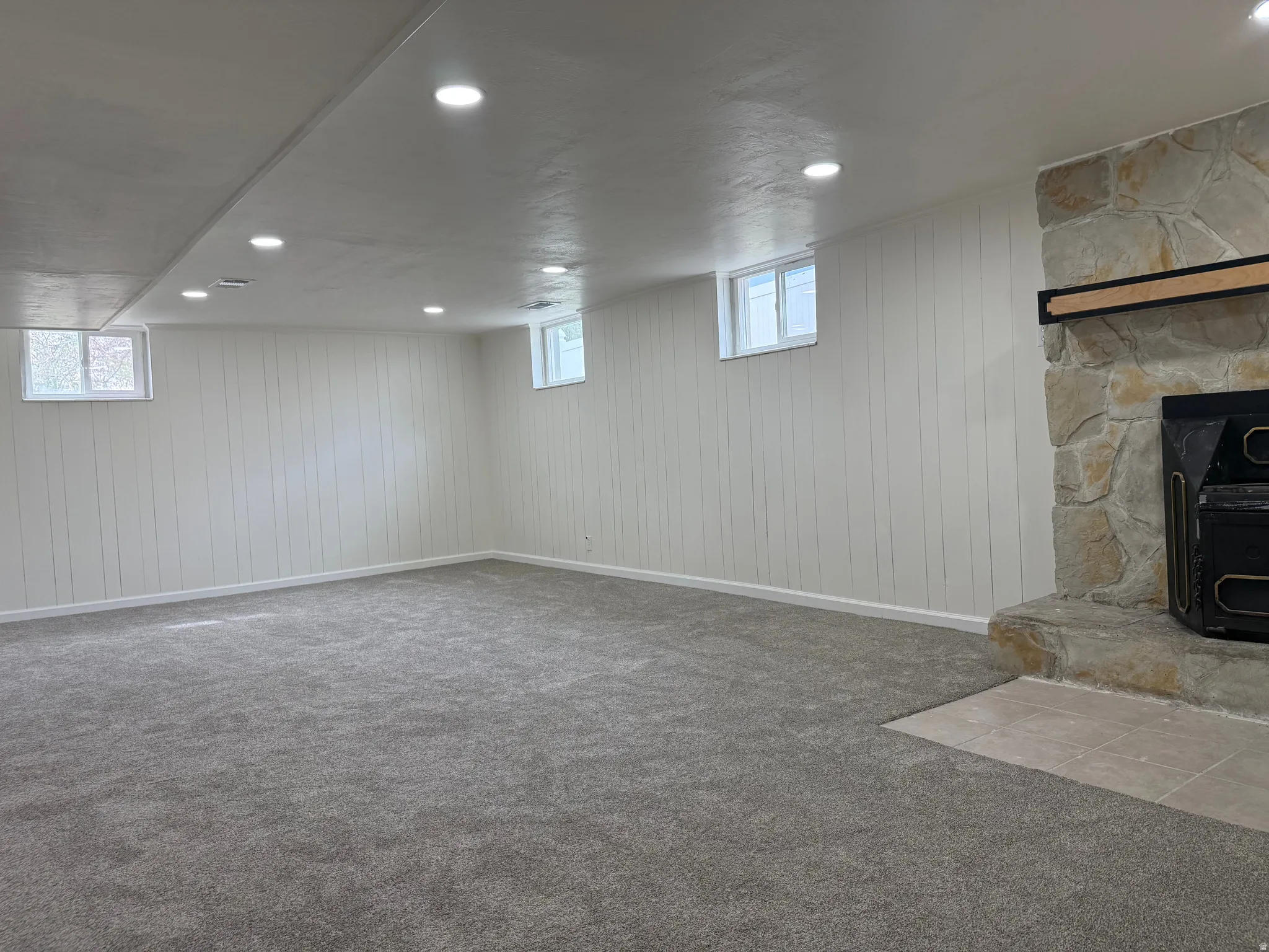 Spacious room featuring new gray carpeting and white vertical paneling