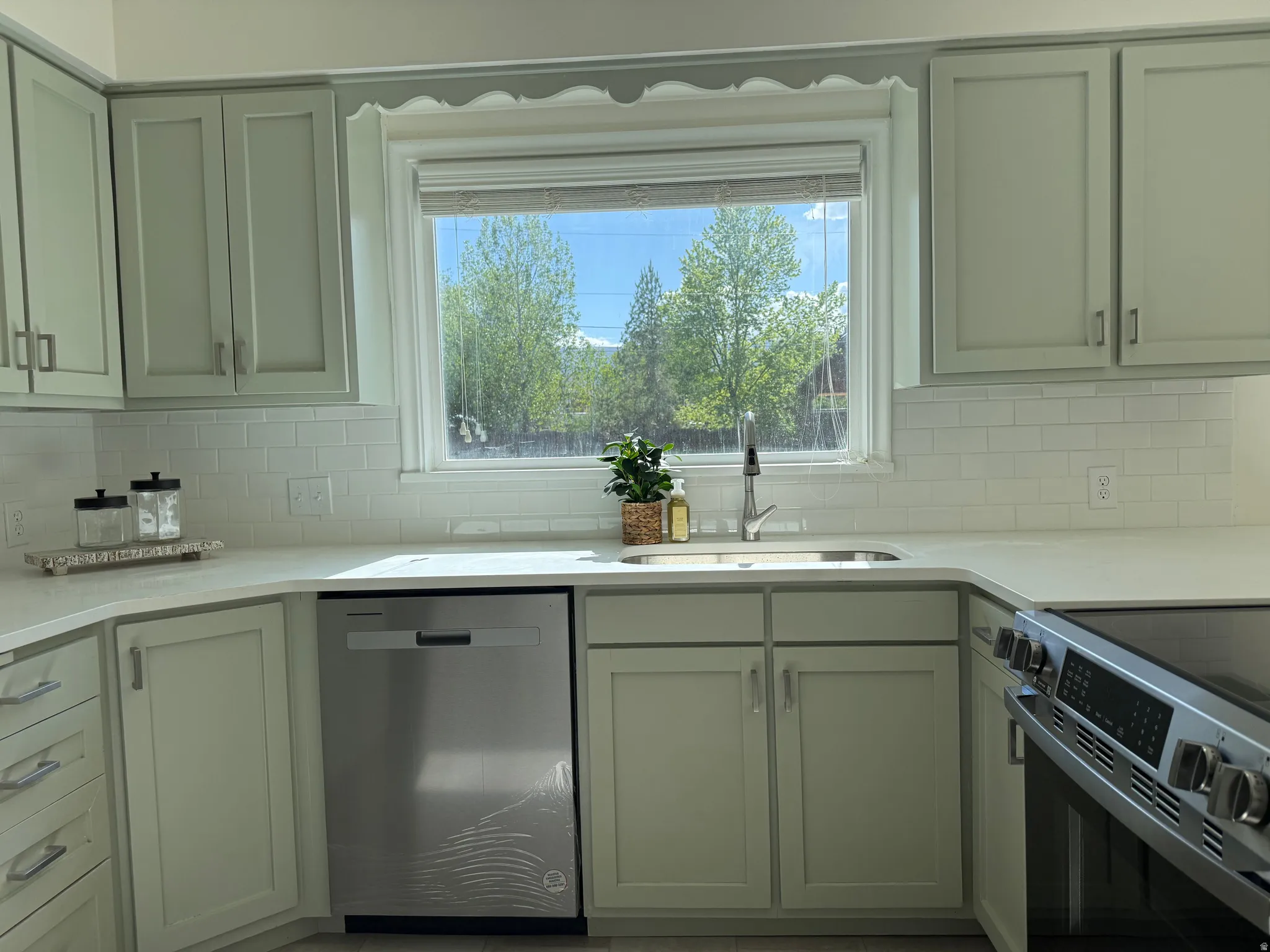 Kitchen featuring light-toned cabinetry, subway tile backsplash, and light-colored countertops
