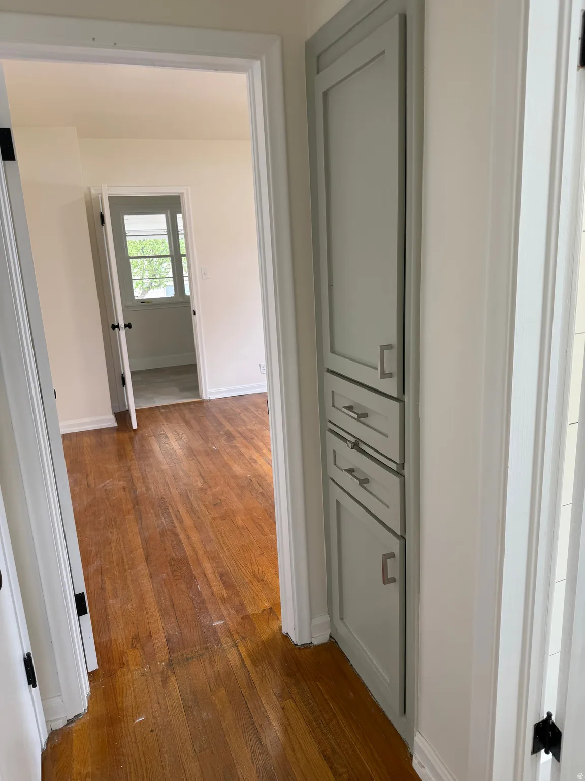 Hallway featuring warm-toned wood-finish flooring