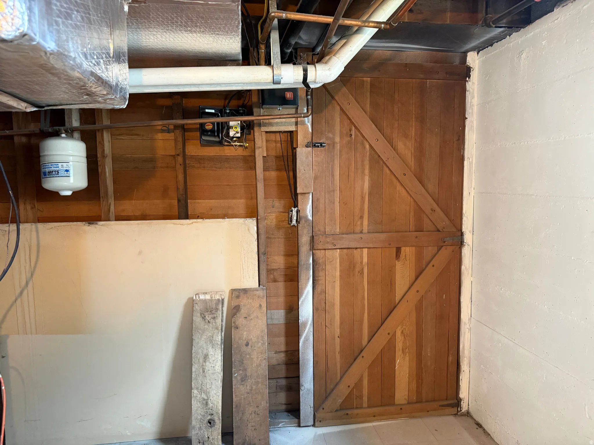 Exposed ceiling utilities with a wood-plank wall and painted concrete block wall